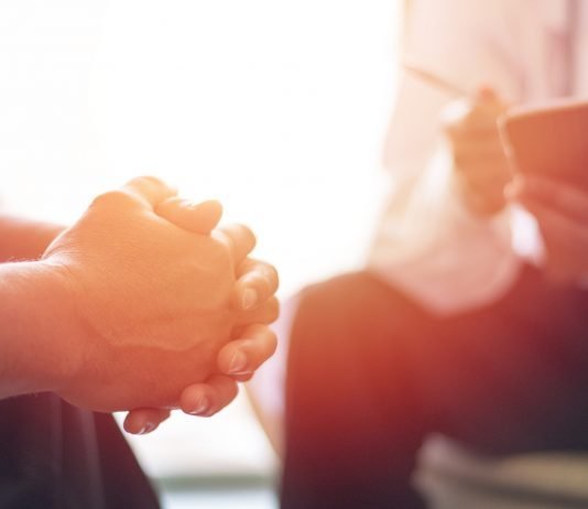 Addressing Cancer-Related Distress for Improved Medical and Psychosocial Outcomes Physician consulting with a patients in hospital exam room.